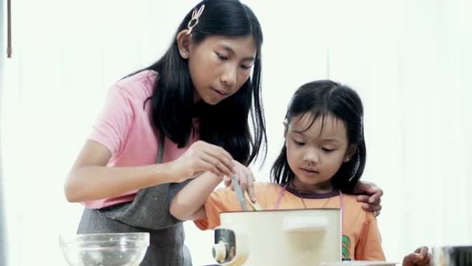 亚洲女孩教姐姐如何在家制作橙色果冻，生活方式概念。