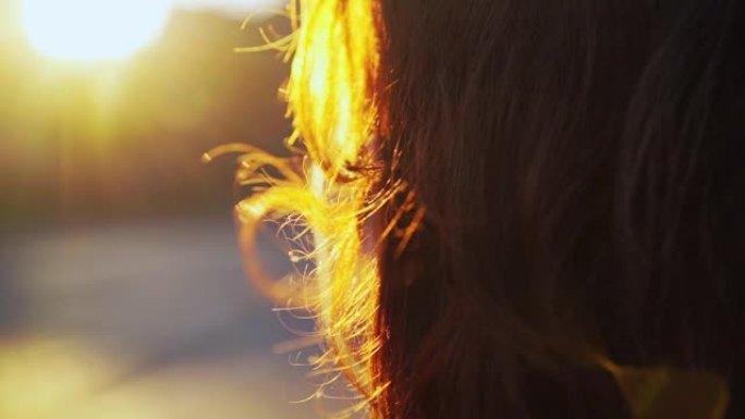 红头发在女人头上的风中挥舞着明亮的日落