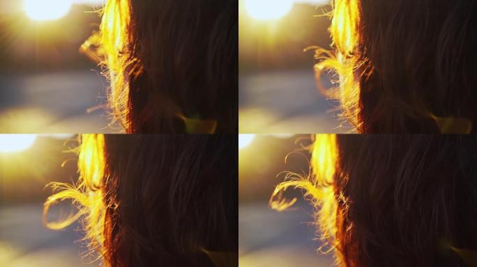 红头发在女人头上的风中挥舞着明亮的日落