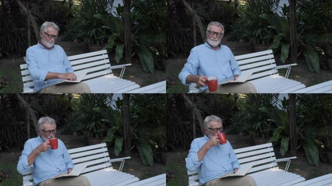 祖父或老人看书独自坐在花园里的长凳上
