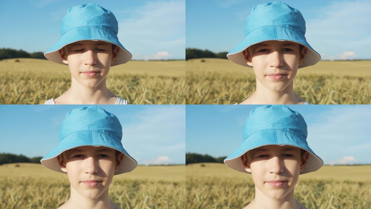 一个滑稽的男孩戴着蓝色的帽子在麦田里看着照相机的肖像