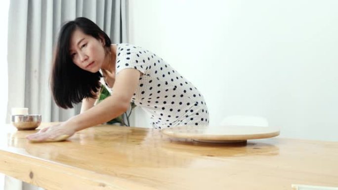 亚洲女性在家靠窗清洁餐桌，生活方式理念。