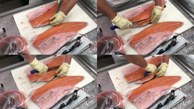 日本专业厨师在手套切割，切片新鲜的生红三文鱼。双手用刀特写。鱼工厂，商店，生产，商业厨房。地中海饮食