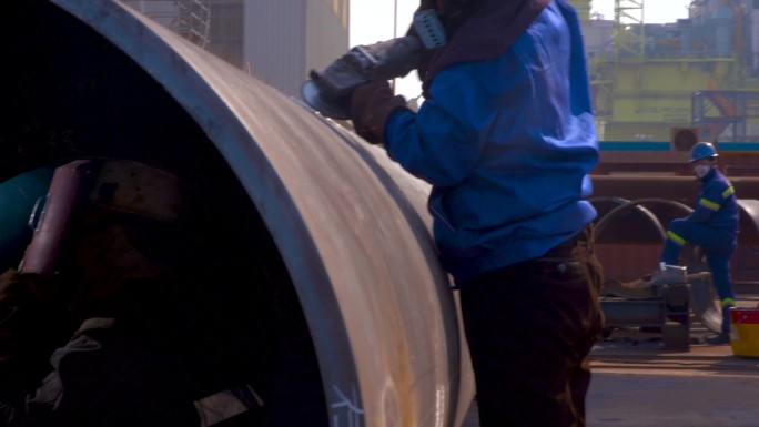 一个在建筑工地工作的男人 一群人站在石油钻井平台前 一个男人正在处理一件设备