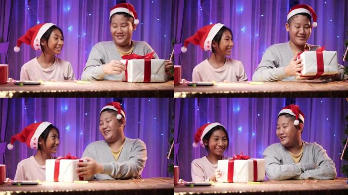 戴着圣诞老人帽子的亚洲男孩和女孩在家里互相交换礼品盒，圣诞灯背景。