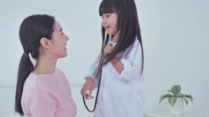 妈妈后视看女儿肩膀上穿着白色医生外套听诊器，和医生想象自己，玩游戏概念