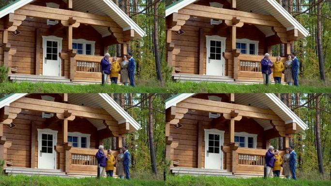 老年夫妇和他们的成年儿子与女友站在乡村木屋附近，愉快地交谈。两代家庭一起度过周末