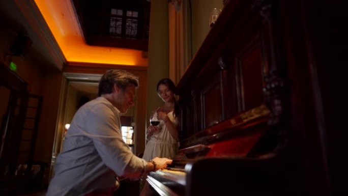 英俊的男人正在为他的妻子弹钢琴