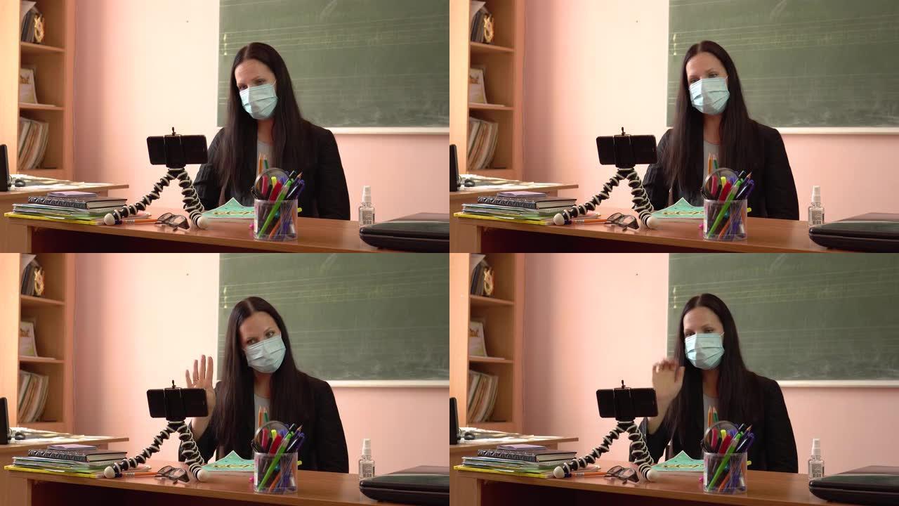 一位年轻的老师上课，用智能手机拍摄自己。戴着防护口罩的女教师。检疫期间的视频教程。新型冠状病毒肺炎