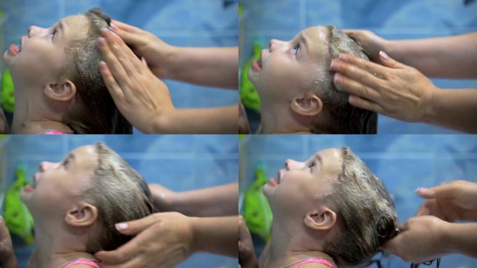 妈妈用婴儿洗发水洗小女儿的头，照顾孩子。