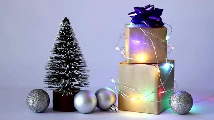 圣诞礼品盒包裹在闪烁的花环中，背景为圣诞树和球。圣诞快乐!假日概念