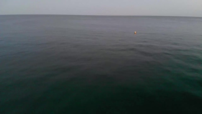 深蓝色的海水在下面闪闪发光。在英国的一个夏夜，一个黄色的浮标在凉爽的水面上上下浮动