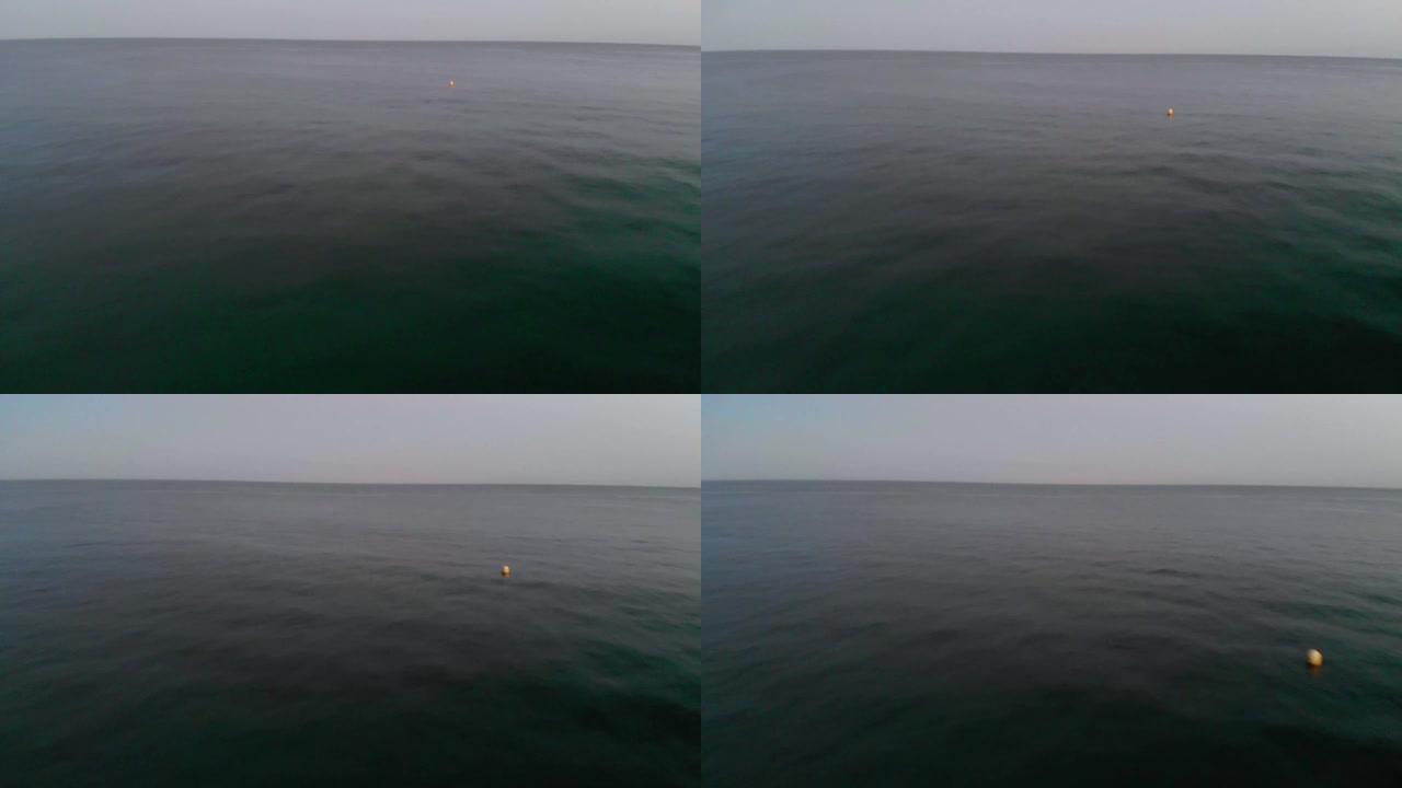 深蓝色的海水在下面闪闪发光。在英国的一个夏夜，一个黄色的浮标在凉爽的水面上上下浮动