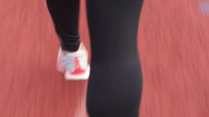 田径训练期间穿着运动紧身衣在赛道上奔跑的跑步者的后视图。