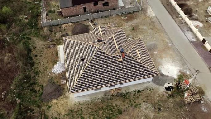 在建的木制屋顶框架结构未完成砖房的鸟瞰图。正在开发中的未完成的砖砌建筑