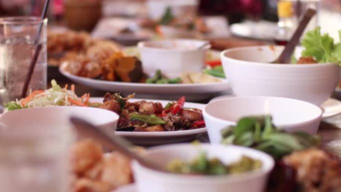 户外餐厅餐桌上的4k泰国食物，白天，朋友聚会，吃午餐，亚洲食物餐桌，一杯水，白色容器，温暖的一天，夏