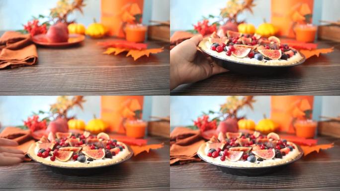 女人的手放在桌子上，新鲜出炉的自制无花果和浆果馅饼和马斯卡彭奶酪。秋收概念。
