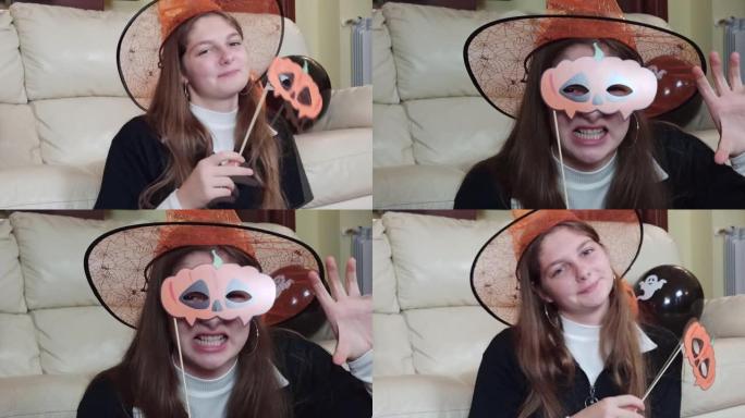 一个微笑的女孩戴着纸面具玩得开心，做鬼脸，在家庆祝万圣节