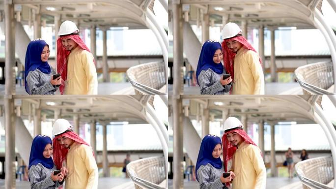 数字营销组阿拉伯人使用智能平板行走在现代穆斯林阿联酋城市触摸屏讨论。亚洲企业家在户外与老板微笑交谈