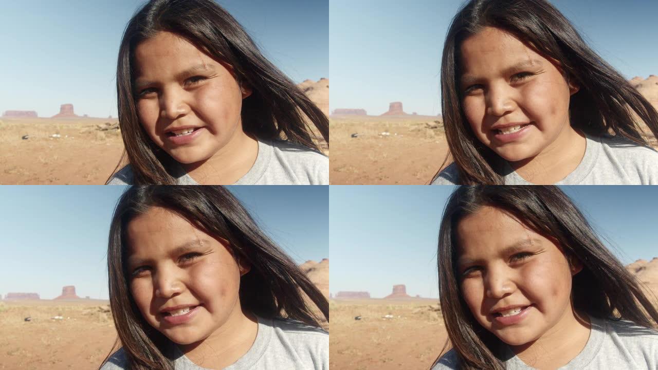 一个年轻的纳瓦霍男孩的肖像在他身后的纪念碑谷中微笑并感到高兴