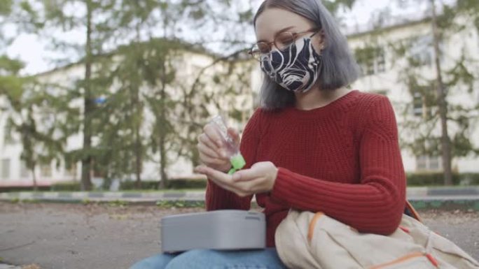 十几岁的学生在吃午餐前戴着可重复使用的防护口罩并使用洗手液