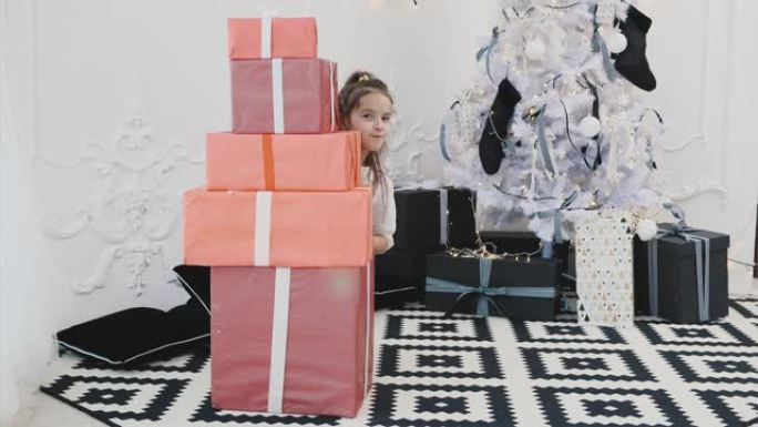 可爱的小女孩玩圣诞礼品盒，建造一个金字塔，从它的后面，从一侧，然后从另一侧向外看。