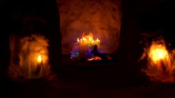 圣诞装置在雪屋内，晚上有五颜六色的冰冷的地方和燃烧的蜡烛