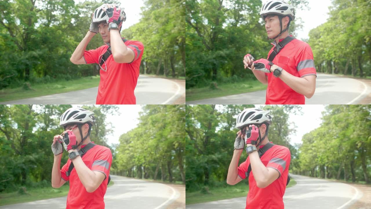 一名男子在骑自行车前最后穿着自行车服，骑自行车手套，头盔和太阳镜。