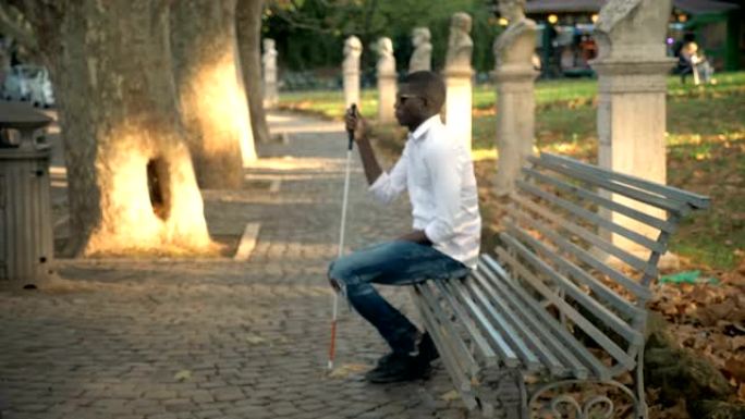 失明，独立。坐在公园长椅上的非洲盲人