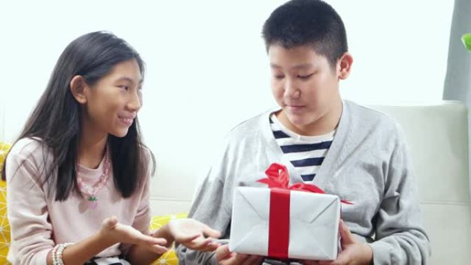 亚洲男孩在家里给妹妹送礼盒，以进行特殊活动。
