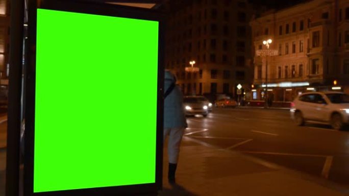 市街。晚上。带有绿色大屏幕的陈列柜。汽车来了。