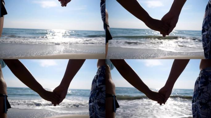 男女双手在美丽的海景背景下互相牵着。一对恋人站在海滩上，携手共进，欣赏风景。在暑假一起度过时光。