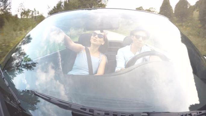 4K挡风玻璃上的夫妇在夏天的一天与女人指着裸露的汽车