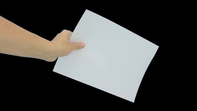 一只手拿着一张白色的空纸A4，黑色背景下有复印空间