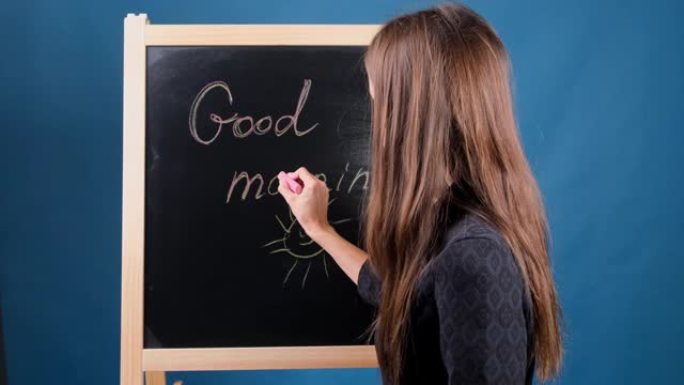 女性在黑板上写下题词早上好。美好的一天概念