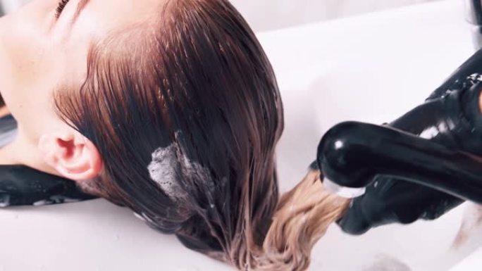 专业护发。理发师用水清洗客户的头发。