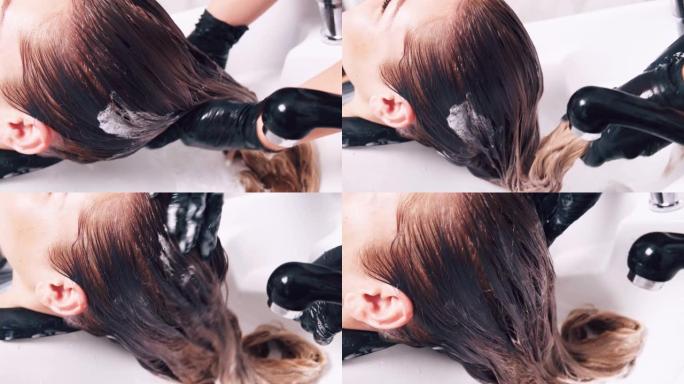 专业护发。理发师用水清洗客户的头发。