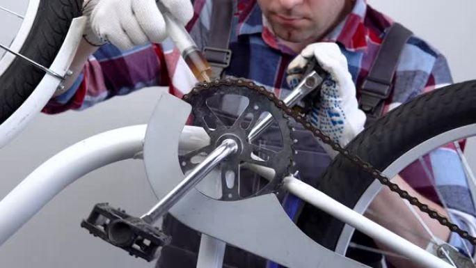 自行车准备。一名男性修理工用刷子润滑自行车链条。