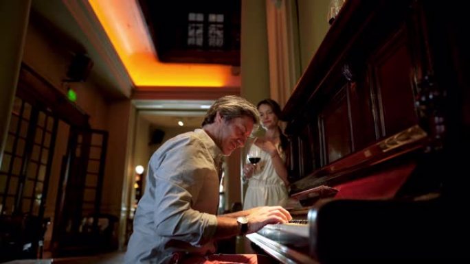 英俊的男人在餐馆为妻子弹钢琴