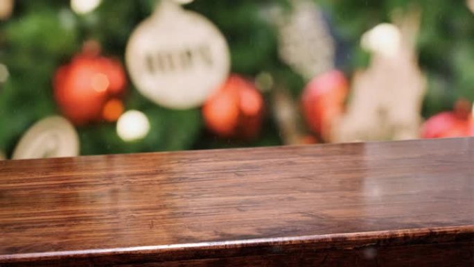 空对角线木制桌面，带模糊绿色圣诞树装饰红色摆设，带雪的细绳背景，用于展示广告产品的节日背景