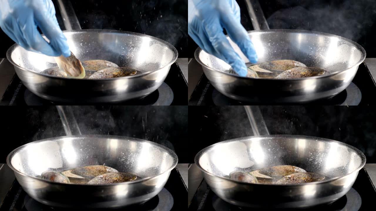 美丽的慢动作食物视频。厨师用蓝色手套将贝类放在热不粘煎锅上。到处都是油。高清