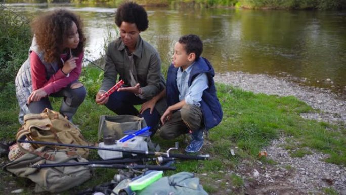 母亲向孩子们展示了他们将使用的不同诱饵和钓具，教他们如何钓到鱼