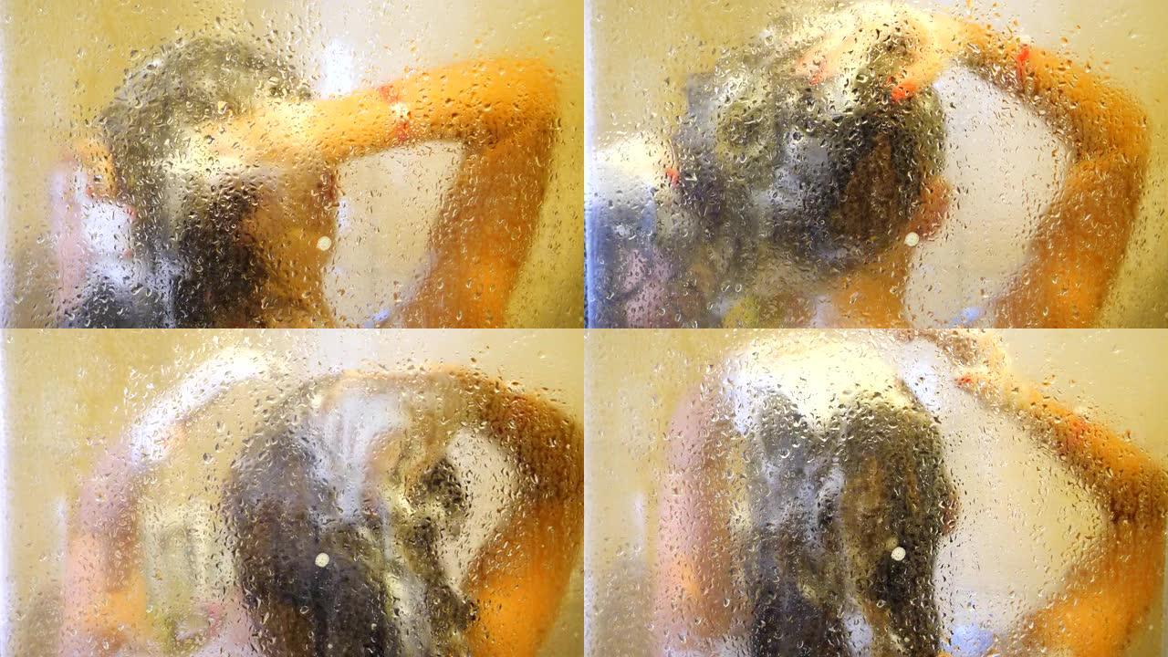 正在洗澡的面目全非的女人。年轻女孩站在淋浴间享受温水。迷人的女士照顾自己洗头。水滴玻璃门上的美景。