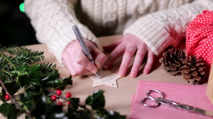 女人在可重复使用的木制礼品标签上书写环保圣诞礼物