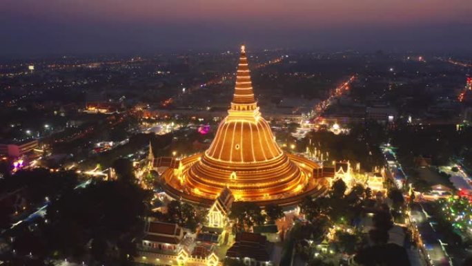 晚上Phra Pathommachedi寺的空中俯视图。带有民居的金色佛教宝塔，泰国纳康帕通区城市。