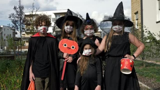 穿着黑色化装的儿童群像。每个人脸上都戴着医用口罩。covid19冠状病毒大流行期间的万圣节