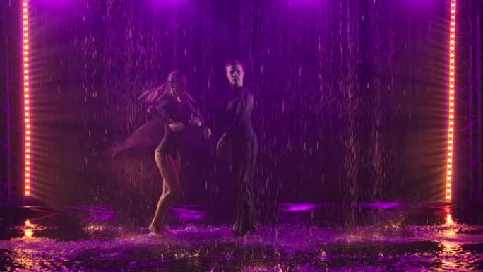 一对激情情侣在雨中表演的Jive元素。在黑暗的工作室里拍摄，背景是紫色的烟雾。慢动作