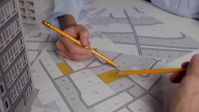 城市规划-商人在地籍图上讨论公寓楼建设的领土建筑地块