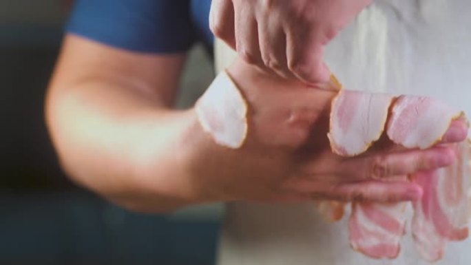 穿着轻便围裙的厨师男子挂在手上多汁的香片猪肉培根