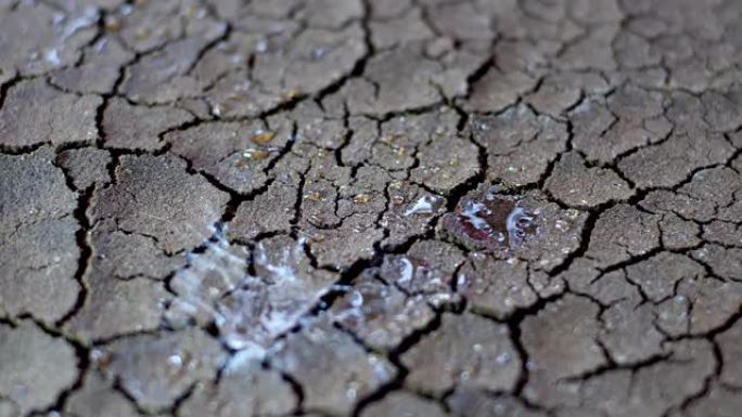 水滴落在干旱的干燥裂隙土壤上